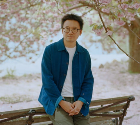 Hua Hsu perched on the back of a park bench
