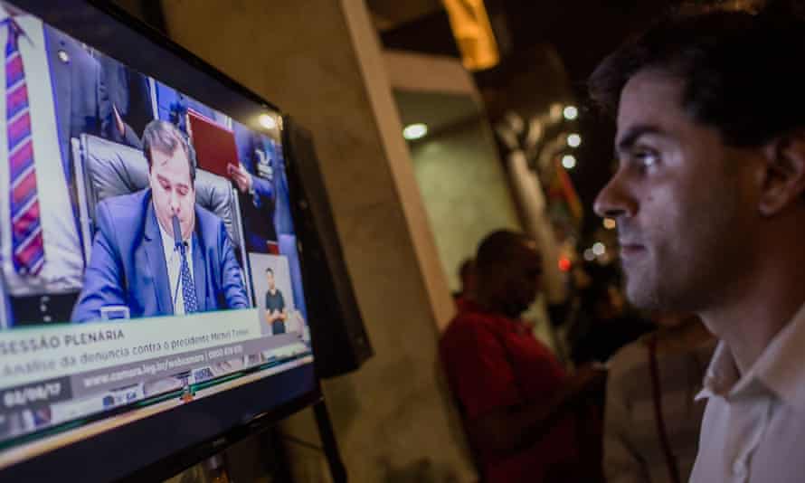 Protesters watch a TV report on the corruption trial against former president Michel Temer, in August 2017.