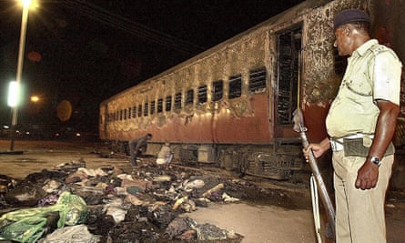 An Indian policeman looks towards a burned-out train coach as belongings of Hindu activists are scattered on the floor