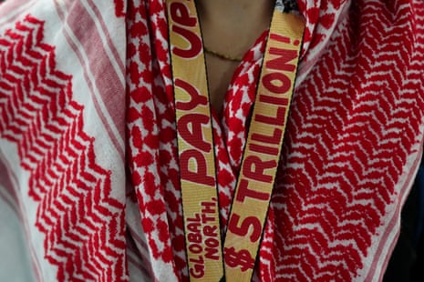 A visitor to Cop29, Dara Shirley Snead, wears a keffiyeh and a lanyard saying: “Global North, pay up $5tr!”