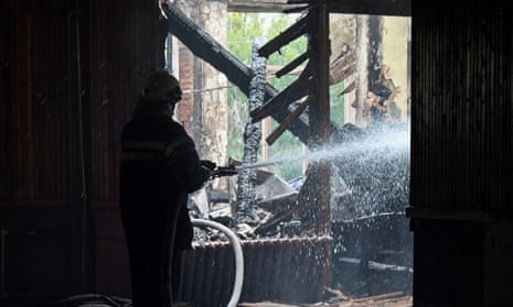 A firefighter extinguishes a blaze at a school in the Ukrainian city of Kharkiv after a missile strike