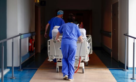 Medical staff transfer a patient along a corridor