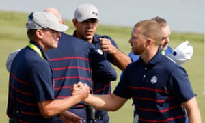 Team USA’s Daniel Berger shakes hands with Team USA captain Steve Stricker on the 17th green as Brooks Koepka looks on after Team USA win the match during the Foursomes.