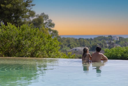 Couple in an infinity pool gazing into a sunset or sunrise