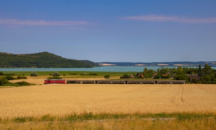 europe's greatest train journeys series Old Hungarian train at Lake Balaton, in a beautiful landscape, with Tihany in the background.