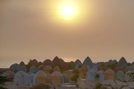 Dome-shaped huts of Hormuz’s Majara hotel cover a hillside at sunset near the sea