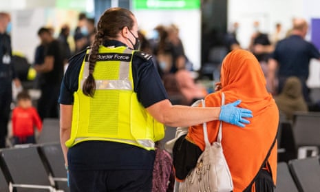 A Border Force worker helps an Afghan refugee after her arrival on an evacuation flight from Afghanistan in August 2021.