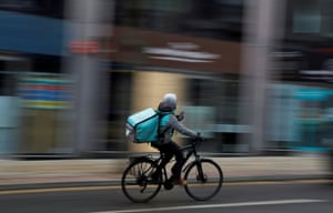 A deliveroo delivery driver cycles through the centre of Manchester.