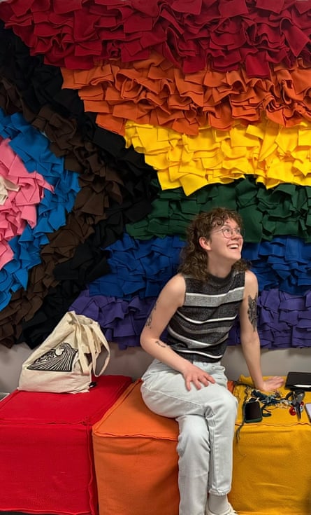 person looks up while smiling in front of trans and lgbtq pride colors