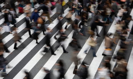 A crowd moves across a pedestrian crossing outside Umeda station, Osaka, Japan