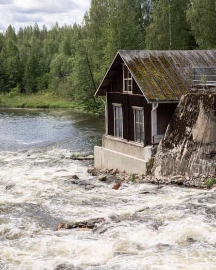 Rapids flowing past brown building amid trees