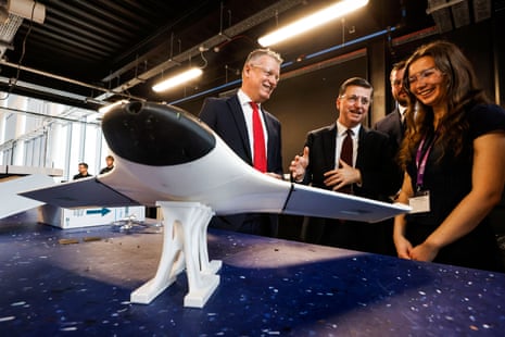 Luke Pollard and Douglas Alexander speaking to a female worker as they look at an experimental drone at an event in Paisley.
