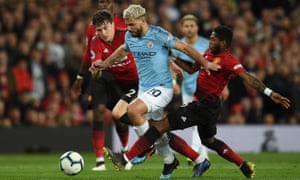 Manchester City striker Sergio Agüero holds off Victor Lindelöf and Fred.