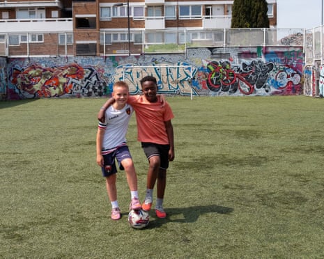 Two boys stand with a football, with their arms around each other