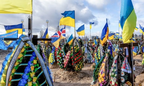 Ukrainian flags are blown by the wind over graves of soldiers killed in combat