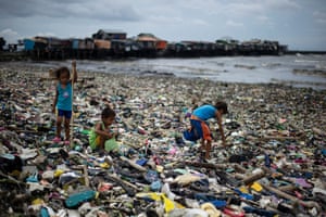 Children collect plastic water bottles from the rubbish washed ashore as a result of typhoon Haima in Manila Bay