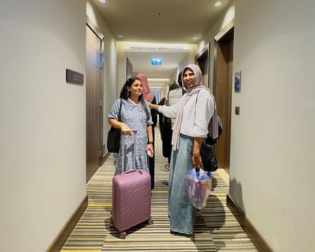 Two South Asian women with suitcases in a hotel corridor