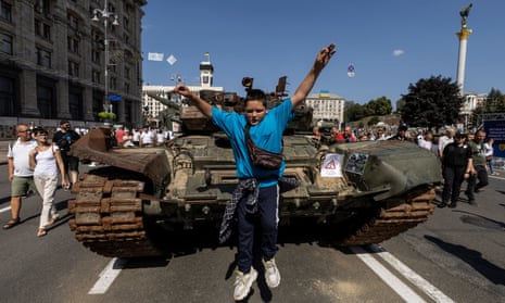 A boy jumps from a tank at an exhibition of destroyed Russian military vehicles and weapons, dedicated to the upcoming country’s Independence Day, in the centre of Kyiv, Ukraine.