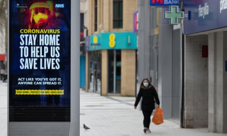 A woman walks passed a NHS sign encouraging people to stay at home on 2 April 2020 in Cardiff.