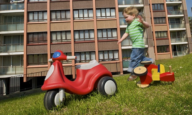 Small boy playing in front of a housing estate