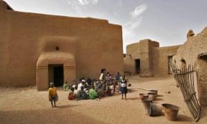 A group of children studying the Koran outside a large earthen mud house, in Djenné.