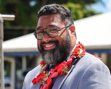 Tonga’s prime minister, Lord Fatafehi Fakafānua, smiles wearing a pale blue suit jacket and a traditional red garland around his neck