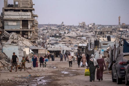 People walk along a path cleared through rubble