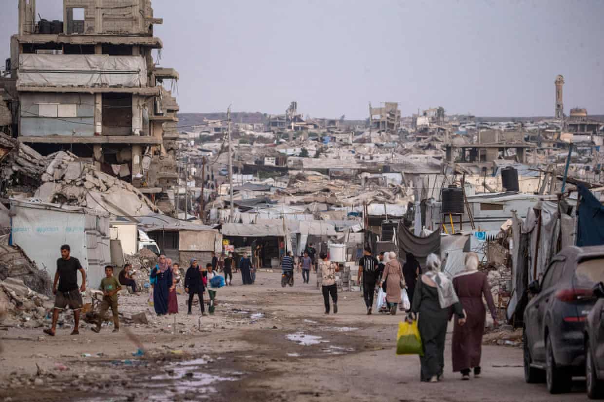 People walk along a path cleared through rubble