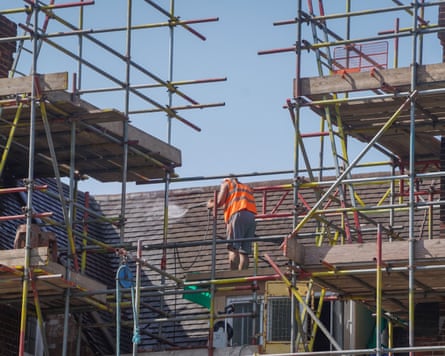 A man stood on scaffolding on the roof of a building