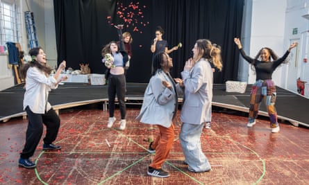 Two actors dance in the centre of a circle of others who are cheering and throwing confetti