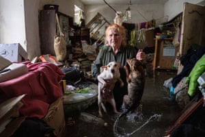 Local resident Tetiana holds her pets, Tsatsa and Chunya, as she stands inside her home that was flooded after the Kakhovka dam was destroyed.