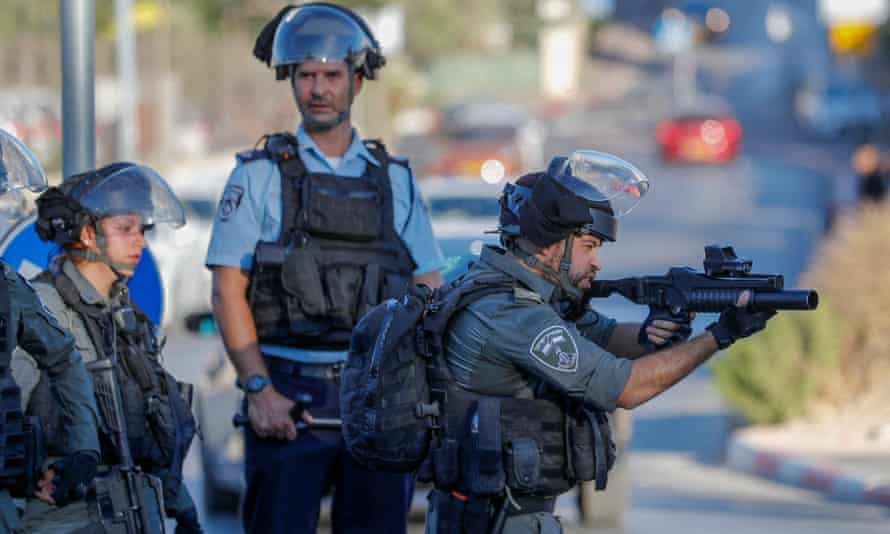 A member of Israeli security forces aims a stun grenade gun at Palestinian protesters in the Sheikh Jarrah neighbourhood of East Jerusalem on 17 July.