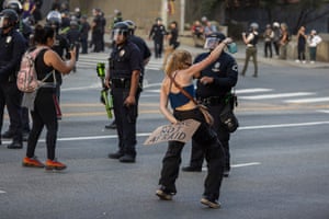 A woman holding a placard reading ‘we are not afraid’ dances in front of riot police officers