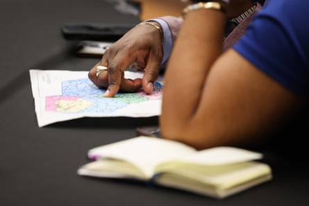 a view of people's arms and hands pointing to a congressional map on a table