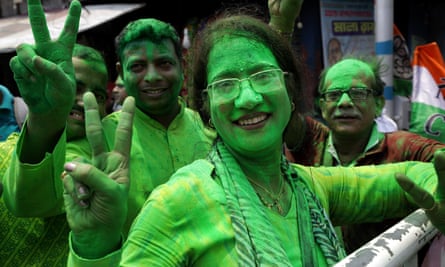Smiling people painted neon green make a V-sign with their fingers