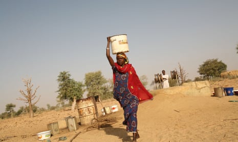 A woman carries water on her head as she returns home with water from a well in Nigeria.