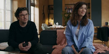 The father and mother sit on a couch in an artfully decorated home.