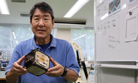 Takao Doi, astronauta y profesor de la Universidad de Kioto, sosteniendo un modelo de ingeniería de LignoSat.