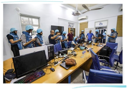 Atef Abu Saif (fourth left) and Bilal Jadallah (third right), wearing plain clothes, stand alongside other people who are wearing blue flak jackets and helmets