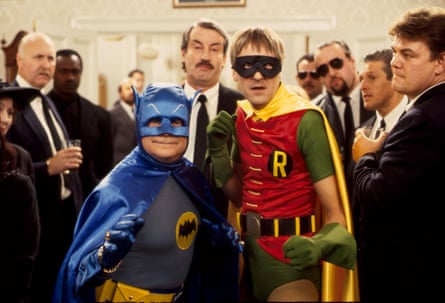 Del and Rodney are dressed in fancy dress as Batman and Robin with a crowd of men in suits behind them