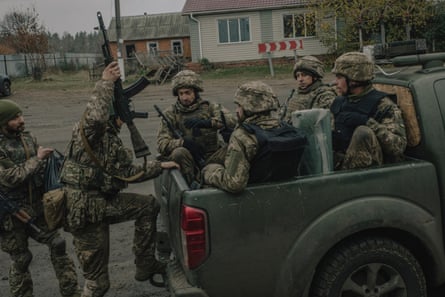Ukrainian soldiers climbing into the back of a pickup truck.