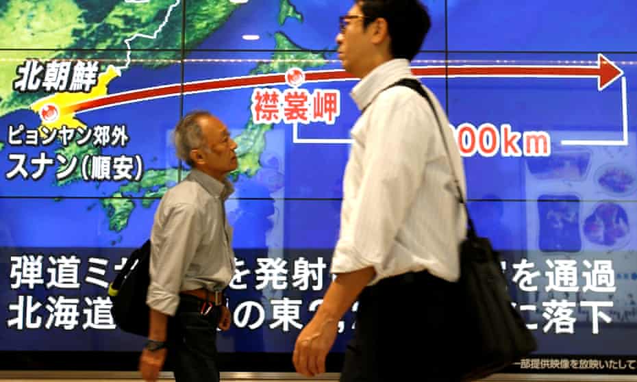 People in Tokyo walk past a TV screen showing the parth of North Korea’s missile.