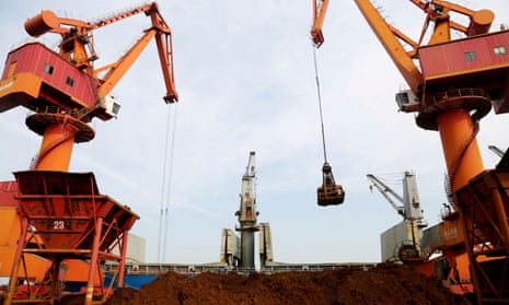 Cranes unloading imported iron ore from a cargo vessel at a port in Lianyungang, Jiangsu province.