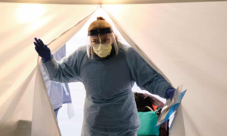 A nurse emerges from a tent with a kit to test for Covid-19 at a drive-through testing station for University of Washington medical center employees in Seattle, Washington.