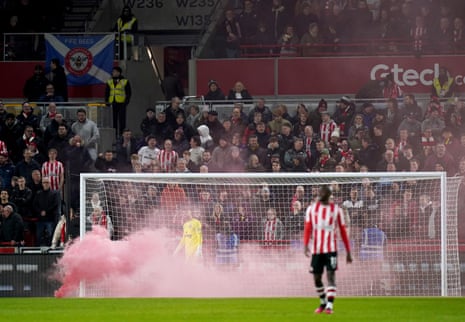 Brentford fans celebrate their first goal by throwing a flare onto the pitch.
