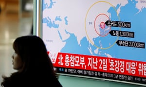 A woman in Seoul walks past a television broadcasting a news report on North Korea firing ballistic missiles.