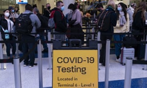 Travellers wait in line for screening near a sign for a Covid-19 testing site at the Los Angeles International Airport in Los Angeles, 24 November.