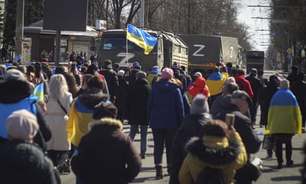 People with Ukrainian flags walk towards Russian army trucks during a rally against the Russian occupation in Kherson, Ukraine, Sunday, March 20, 2022