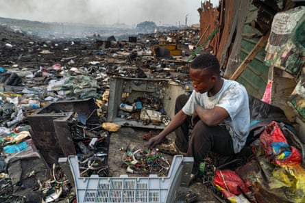 Emmanuel Akatire sits among a large pile of e-waste