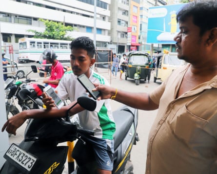 A man checks the national fuel pass of another man on a moped at a gas station in Colombo